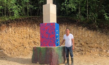 Alexander Lee, artiste qui pose devant l'une de ses oeuvres