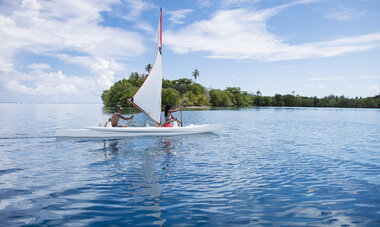 Stephan Lambert faisant de la rame sur une pirogue à voile, accompagné d'une personne 