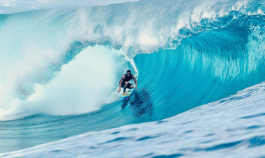 Homme surfant une vague d'un bleu turquois